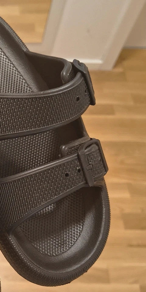 Schwarze Slipper mit zwei verstellbaren Schnallen, leichtes Synthetikmaterial, strukturierte Innensohle.