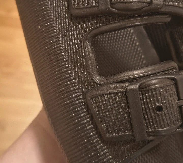 Schwarze Slipper mit zwei verstellbaren Schnallen, leichtes Synthetikmaterial, strukturierte Innensohle.