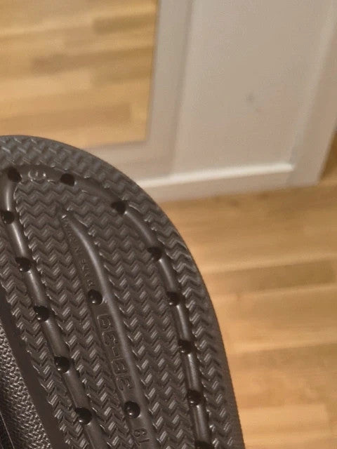 Schwarze Slipper mit zwei verstellbaren Schnallen, leichtes Synthetikmaterial, strukturierte Innensohle.