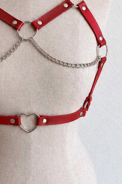 Outfit red body harness with silver metal rings, studs, and decorative chains.