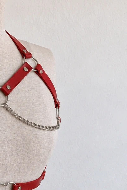 Outfit red body harness with silver metal rings, studs, and decorative chains.