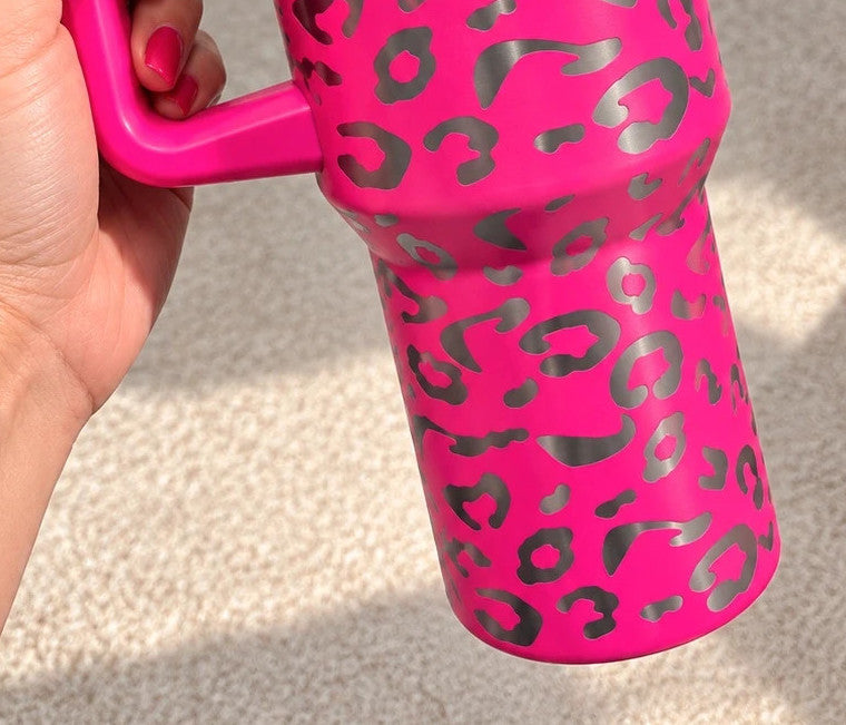 Pink tumbler with leopard print design, insulated, featuring handle and matching lid.