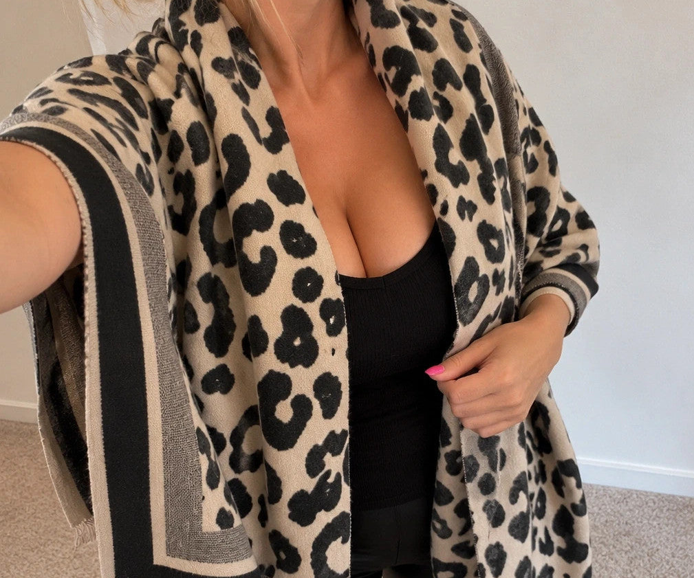 Beige scarf with black leopard print, fringed edges, reversible design, soft polyester material.