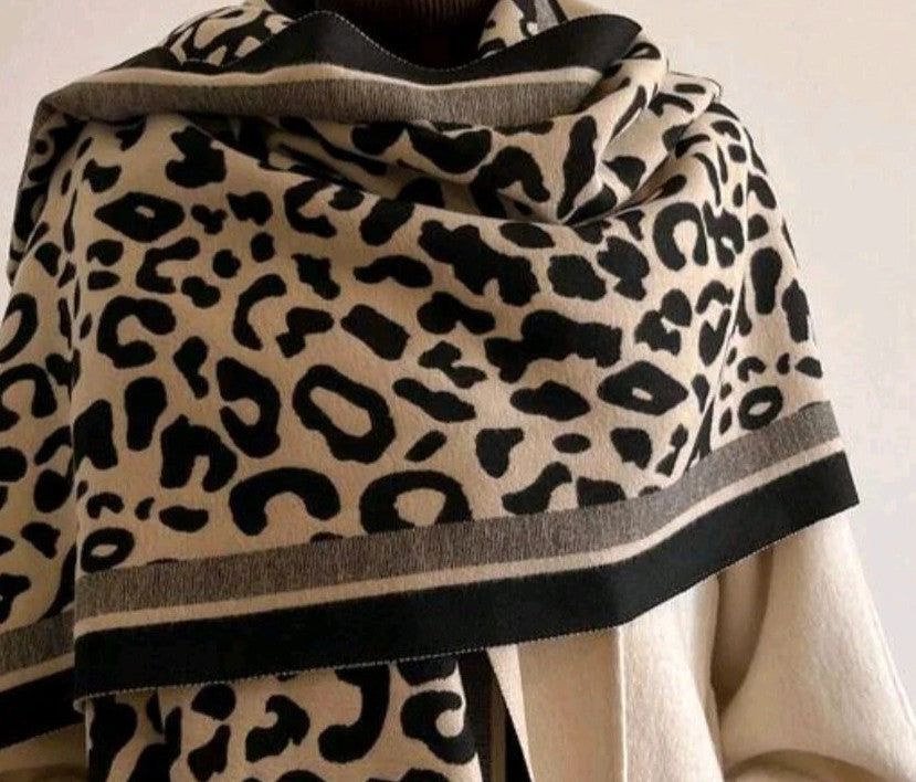 Beige scarf with black leopard print, fringed edges, reversible design, soft polyester material.