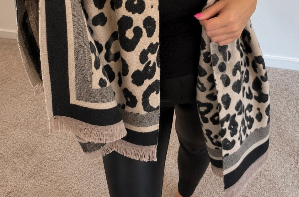 Beige scarf with black leopard print, fringed edges, reversible design, soft polyester material.