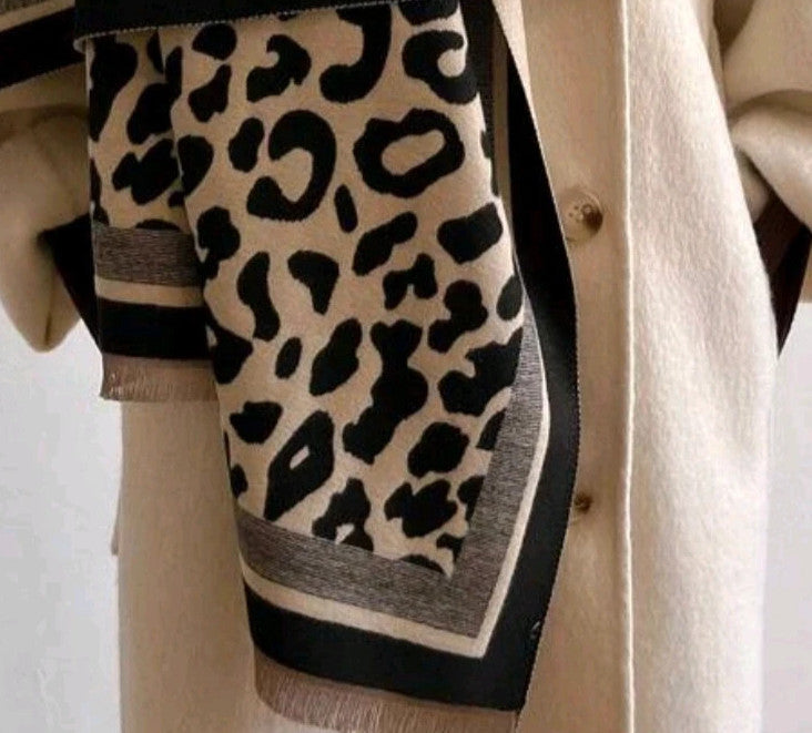 Beige scarf with black leopard print, fringed edges, reversible design, soft polyester material.