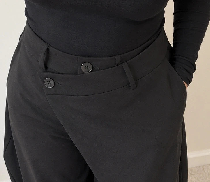 Wide leg black trousers with asymmetrical wrap design and overlapping waistband.